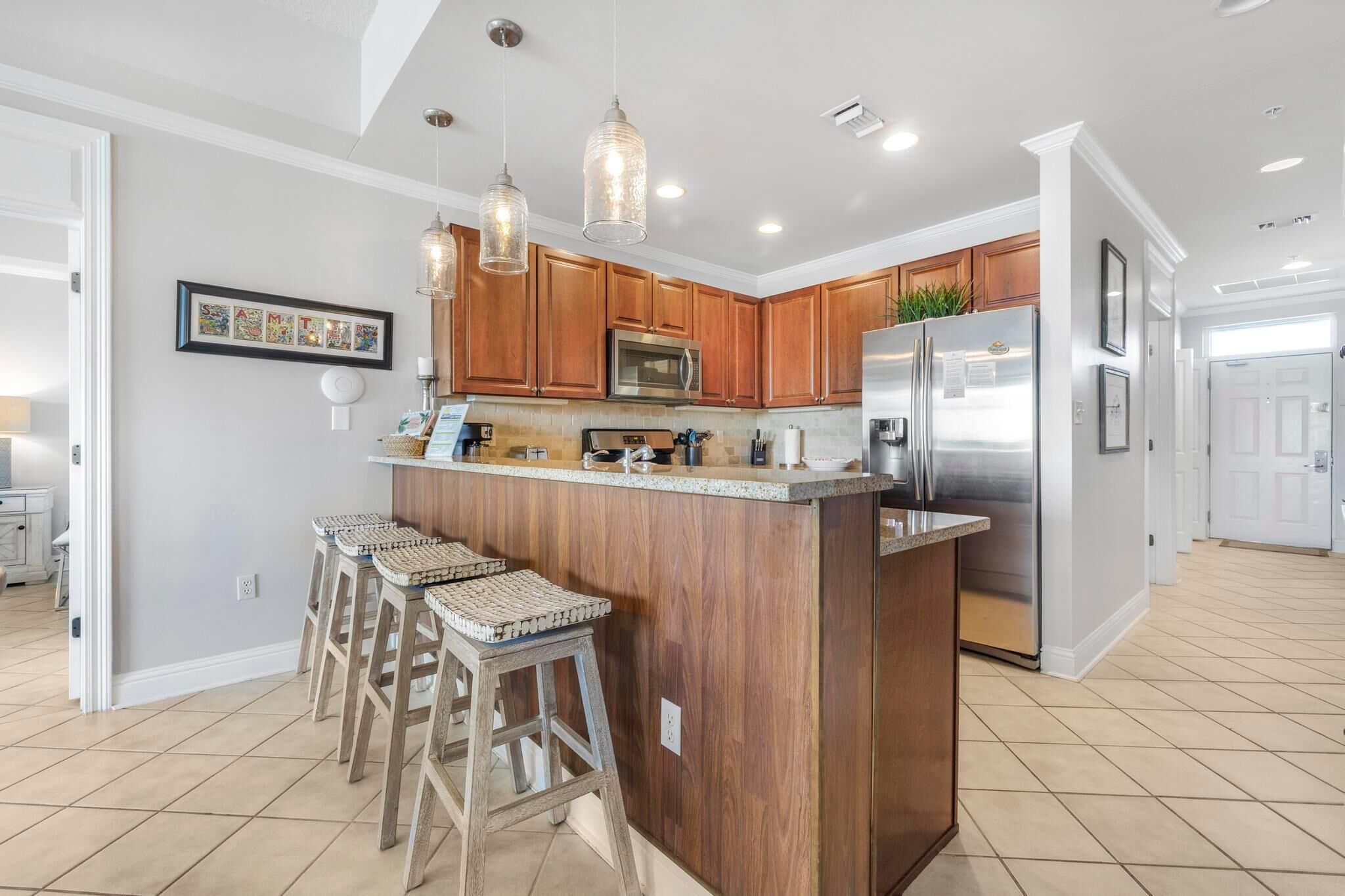 A modern kitchen with wooden cabinets, stainless steel appliances, and a central island with bar stools.