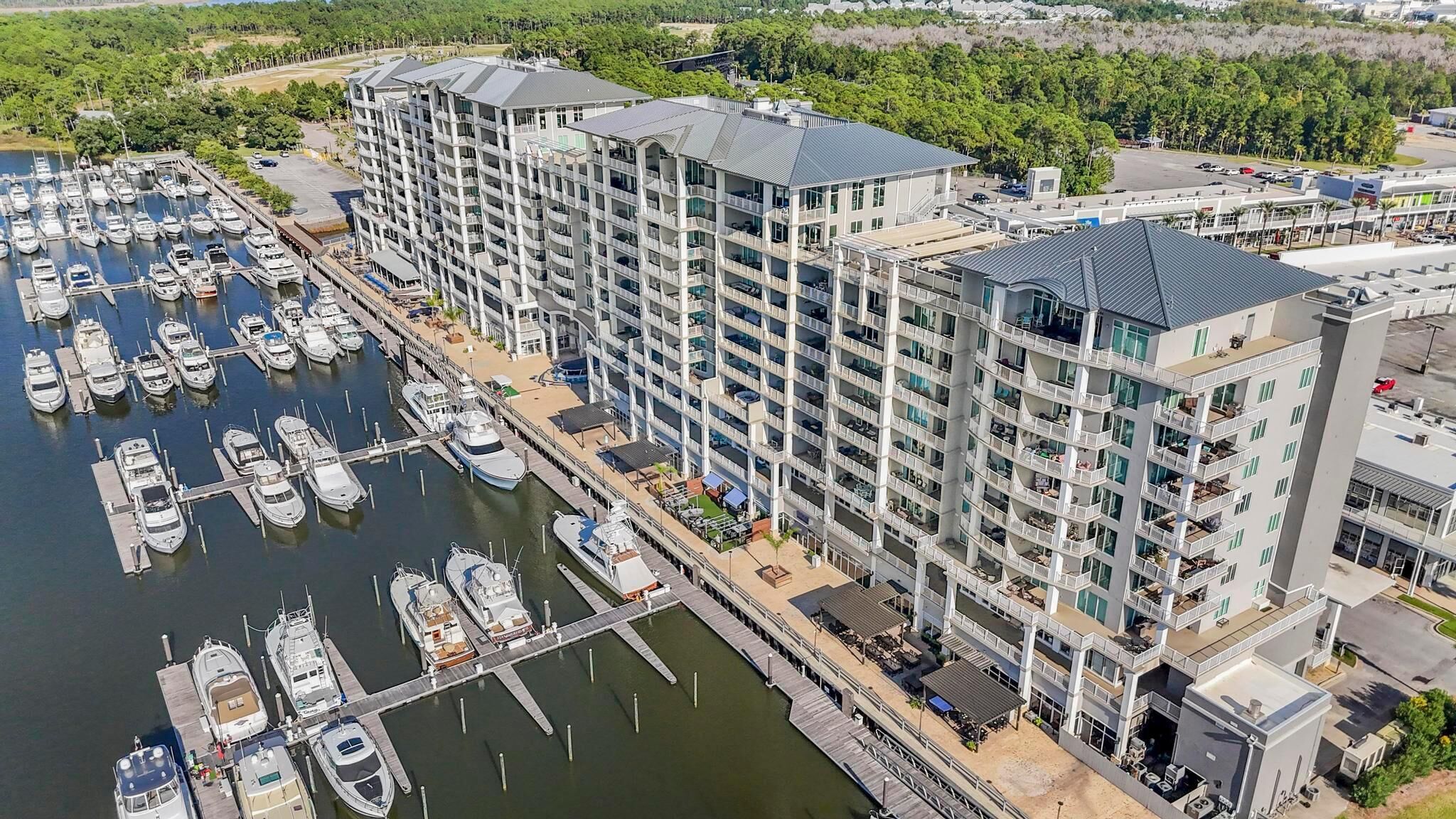 Un hôtel de grande hauteur doté de nombreux balcons, une marina avec de nombreux bateaux et un parking.
