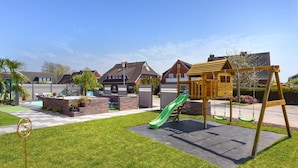 Een woonwijk met een speeltuin, een zwembad en huizen.