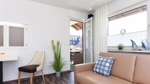 A modern living room with a sofa, a chair, a small table, and a potted plant. - Ferienwohnung mittendrin in Bensersiel (Bensersiel)