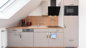 Eine kompakte Küche mit Einbau-Mikrowelle, Kaffeemaschine und Geschirrspüler.