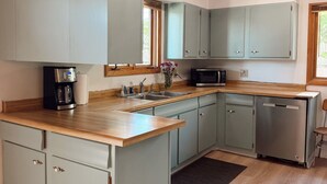 A kitchen with light blue cabinets, a wooden countertop, and a built-in microwave. - Main Street Retreat - Beautiful Home (Miles City)