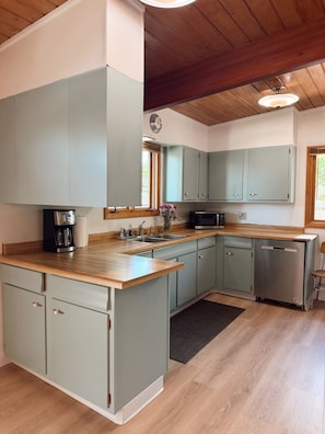 Una cucina con mobili azzurri, un piano di lavoro in legno e un forno a microonde integrato.