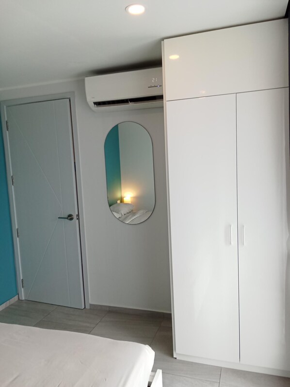 A bedroom with a bed, a wardrobe, a door, and a wall-mounted mirror. - Stylish Urban Escape 1Bed Apt T2-822 (Chalong)
