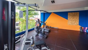 A gym with exercise equipment, a large window, and a blue and orange wall. - Stylish Urban Escape 1Bed Apt T2-822 (Chalong)