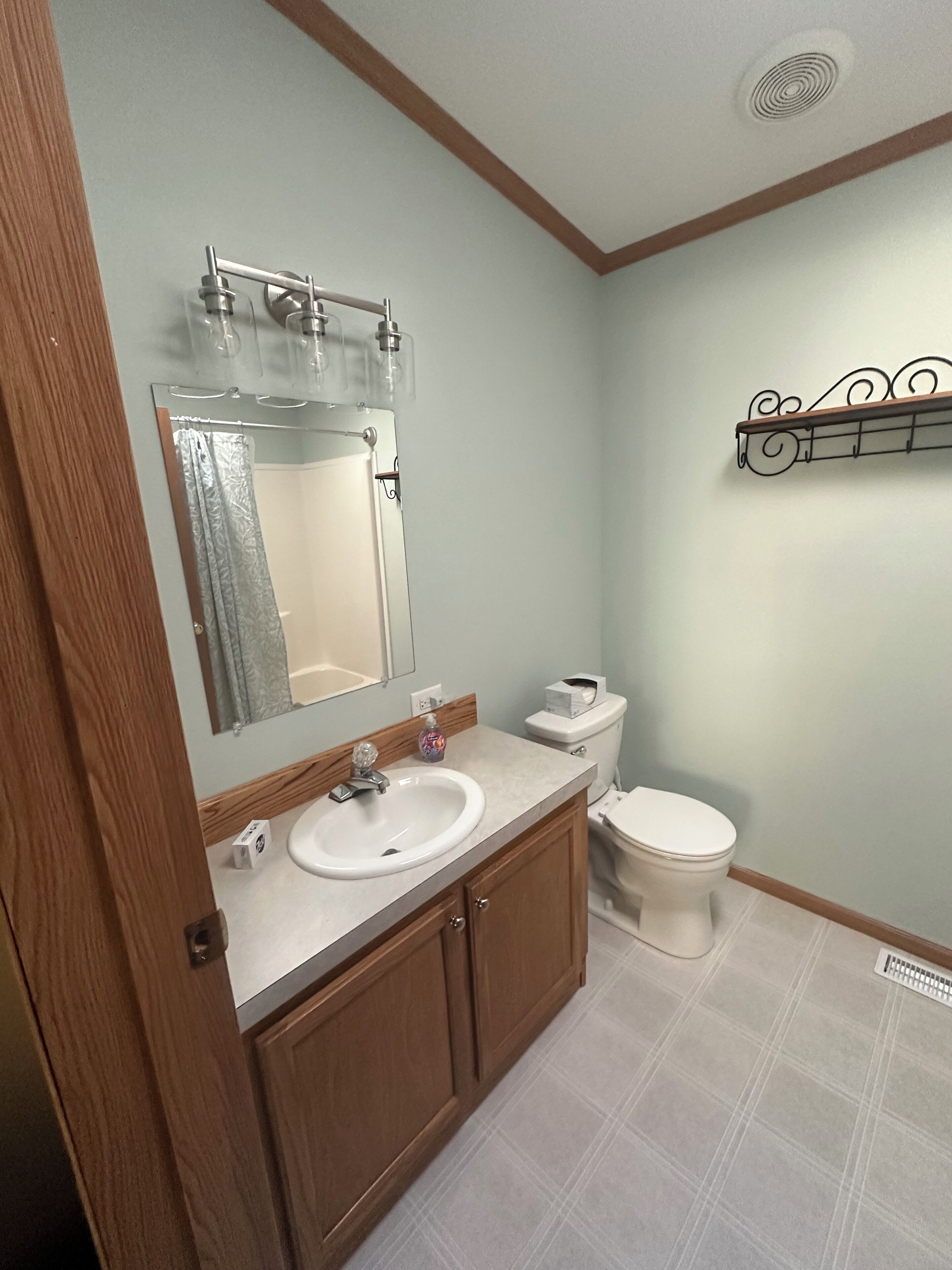 A bathroom with a wooden vanity, white sink, and a toilet.
