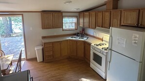 Una cocina compacta con gabinetes de madera, una estufa a gas y un refrigerador.