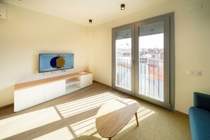 A modern living room with a flat-screen TV, a wooden coffee table, a sofa, and a sliding glass door leading to a balcony. - Sun & Moon Aparthotel (El Prat de Llobregat)