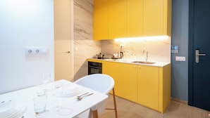 Una cocina moderna con armarios amarillos, encimera blanca y horno empotrado.