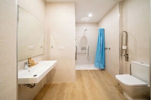 A modern bathroom with a white sink, a shower with a blue curtain, and a toilet. - Sun & Moon Aparthotel (El Prat de Llobregat)