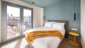 Un dormitorio moderno con una cama grande, una mesita redonda pequeña y vistas a través de una puerta corredera.