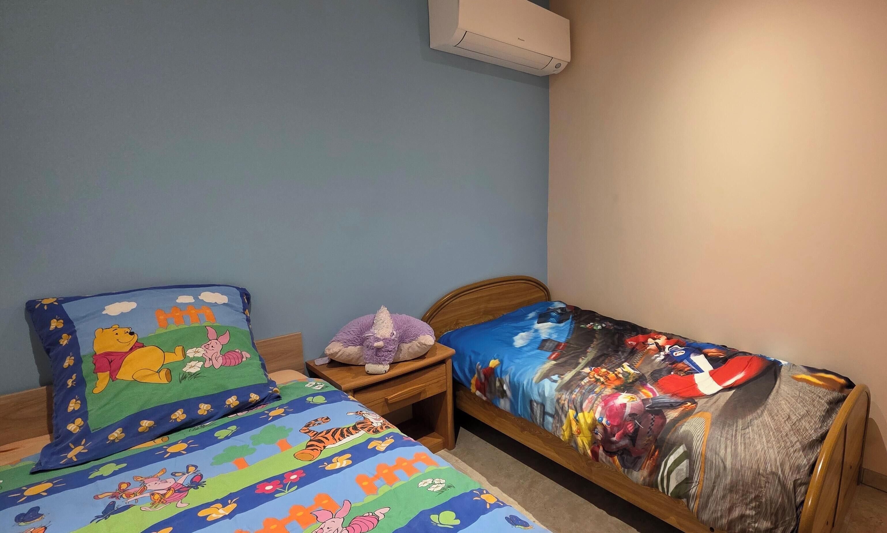 Een slaapkamer met twee bedden, elk met een uniek dekbed.