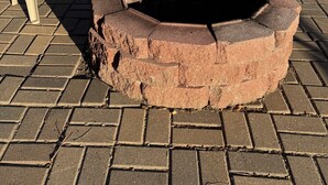 Two plastic chairs with decorative cushions, a brick fire pit, and a grassy field in the background. - Studio House - Central Location (Miles City)