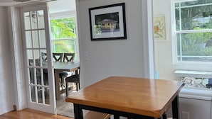 Ein Essbereich mit einem Holztisch und Bänken, einem gerahmten Bild an der Wand und einem Fenster mit Blick ins Grüne.
