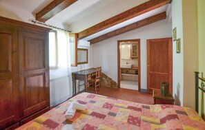 A bedroom with a bed, a desk, a chair, a wardrobe, and a bathroom visible through an open door. - Nice home in Bucine with house a panoramic view (Bucine)