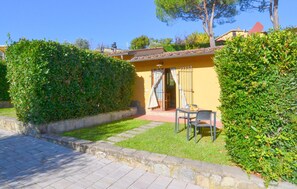A small, yellow building with a tiled roof, a door with curtains, and a table with chairs outside. - Nice home in Bucine with house a panoramic view (Bucine)