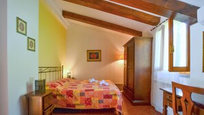 Ein Schlafzimmer mit einem Bett, einem Holzstuhl, einem Kleiderschrank und einer Lampe.