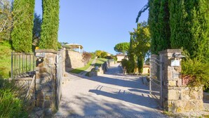 Ein gepflasterter Weg führt zu einem verschlossenen Eingang, im Hintergrund ist ein Wohngebiet sichtbar.