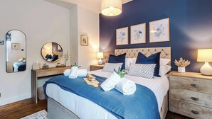 A modern bedroom with a bed, bedside tables, a mirror, and framed artwork on the wall. - Beautiful Cozy Cottage Home in Sandbach, Sleeps 4! (Cheshire East)