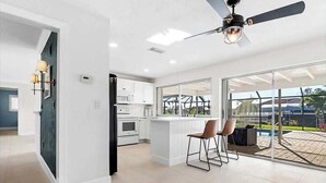 A modern kitchen with white cabinets, a central island, and a ceiling fan. - European Artistic Retreat (Cape Coral)
