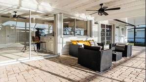 An open-plan living area with glass doors, wicker furniture, and ceiling fans. - European Artistic Retreat (Cape Coral)