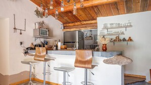 A kitchen with a central island, bar stools, and hanging light fixtures.