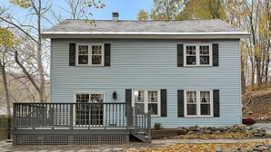 A two-story house with a front deck and stone wall.