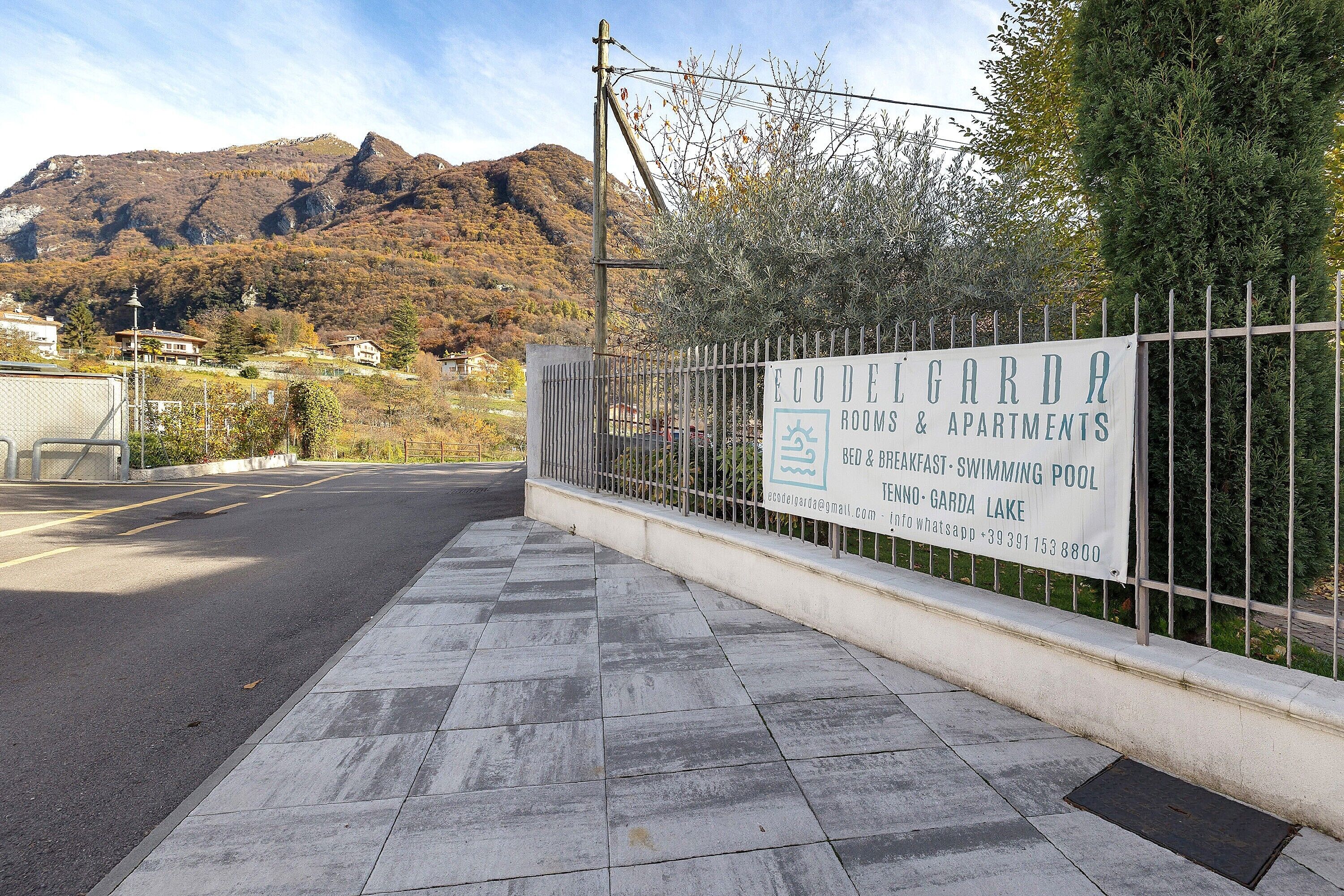 A sign for EcoDelGarda Apartments with amenities like a swimming pool and breakfast.