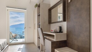 A modern bedroom with a balcony, a desk, and a chair. - Eco del Garda – Room 306 – with Covered Terrace and Lake View (Tenno)