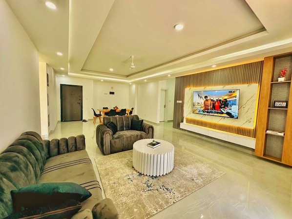 A modern living room with a sofa, a round coffee table, and a television. - Nyali Holiday Apartments Aqua Garden (Mombasa)