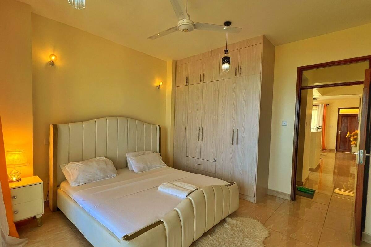 Ein Schlafzimmer mit einem Bett, einem Kleiderschrank, einem Deckenventilator und einem Nachttisch mit Lampe.