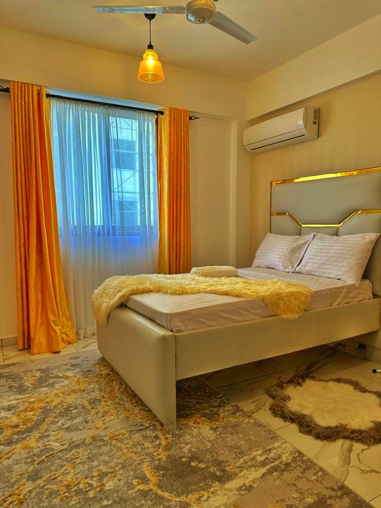 A bedroom with a bed, curtains, a ceiling fan, and an air conditioning unit.