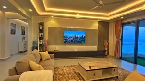 Una sala de estar moderna con una televisión de pantalla plana, un sofá, una mesa de centro y vistas al océano.