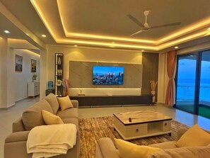 A modern living room with a flat-screen TV, a sofa, a coffee table, and a view of the ocean. - Nyali Holiday Apartments Aqua Garden (Mombasa)