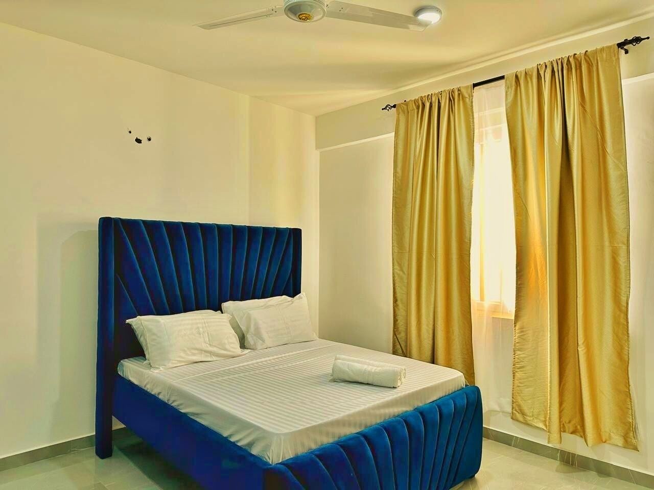 A bedroom with a bed, a ceiling fan, and curtains.