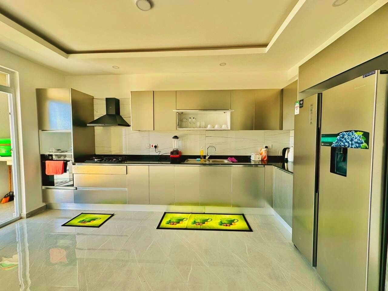 Una cocina moderna con electrodomésticos de acero inoxidable, una isla central y un refrigerador con dispensador de frutas.