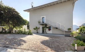 A modern building with a two-story balcony, a staircase, and a paved courtyard. - Eco del Garda - Room 307 - bright with skylights (Tenno)