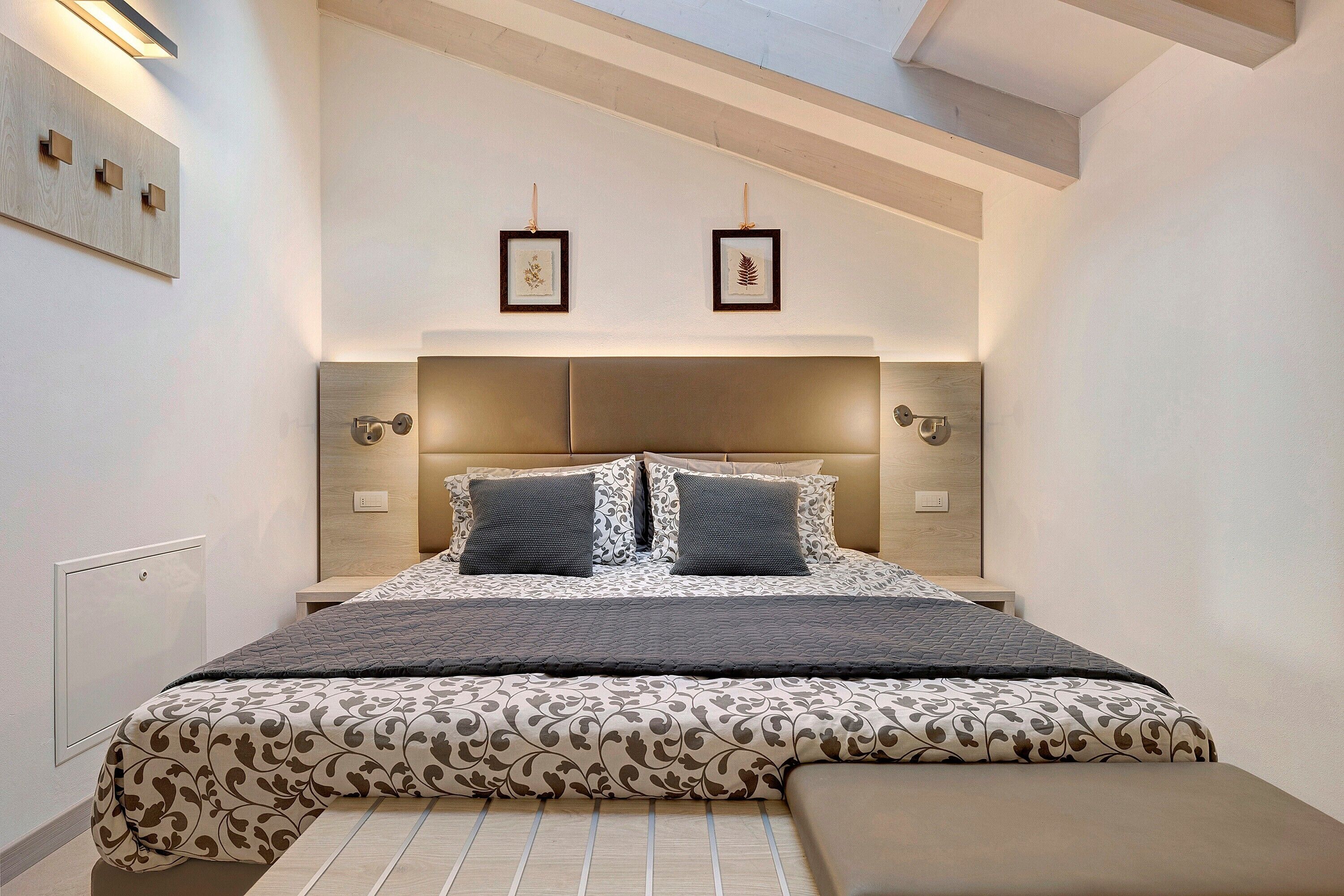 Een moderne slaapkamer met een groot bed, een bankje en een dakraam.