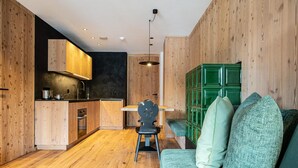 Una cocina moderna con armarios de madera, un comedor con mesa y sillas, y una zona de estar verde.