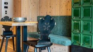 Una habitación revestida de madera con una mesa de comedor, sillas, un banco tapizado de verde y una lámpara colgante.