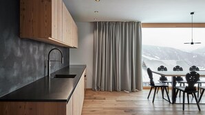 A modern kitchen with wooden cabinets, a black countertop, and a dining area with a table and chairs.