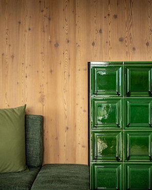 Une pièce avec un mur en bois, un meuble vert et un canapé vert agrémenté d’un coussin vert.