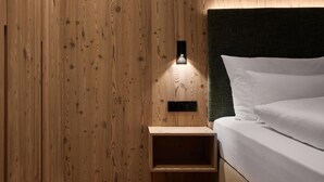 Ein Zimmer mit Holzwandverkleidung, einem Bett, einem Nachttisch und einer Wandleuchte.