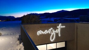 En bygning med en neonskilte der siger 'marzit' mod et sneklædt landskab i skumringen.