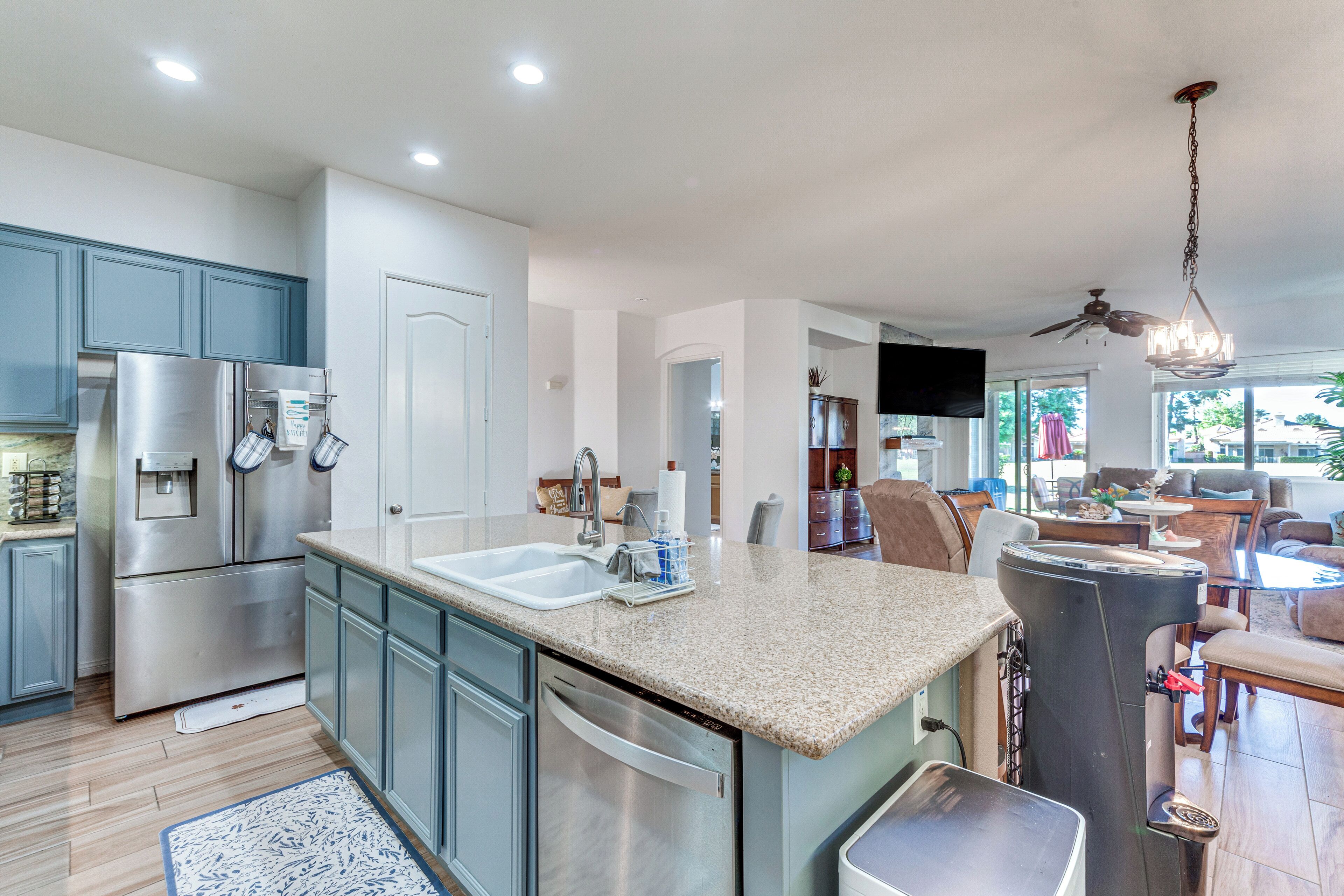 A modern kitchen with stainless steel appliances, a granite countertop, and a dining area with a ceiling fan and natural light.
