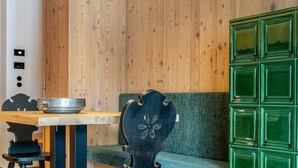 A modern interior with a wooden wall, a green cushioned bench, a dining table with chairs, and a hanging light fixture. - Apartment 202 with Private Balcony and Shared Garden (Maranza)