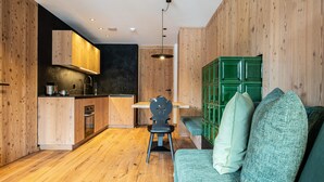 A modern kitchen with wooden cabinetry, a dining area with a chair, and a green seating area. - Apartment 202 with Private Balcony and Shared Garden (Maranza)