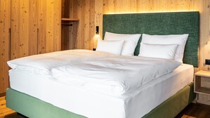 A bed with white bedding, a green upholstered headboard, and a wooden floor. - Apartment 202 with Private Balcony and Shared Garden (Maranza)