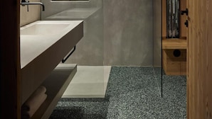 A modern bathroom with a wooden ceiling, a large mirror, a sink, and a shower area.