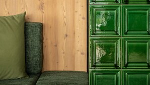 A room with a wooden wall, a green cabinet, and a green sofa with a green pillow.